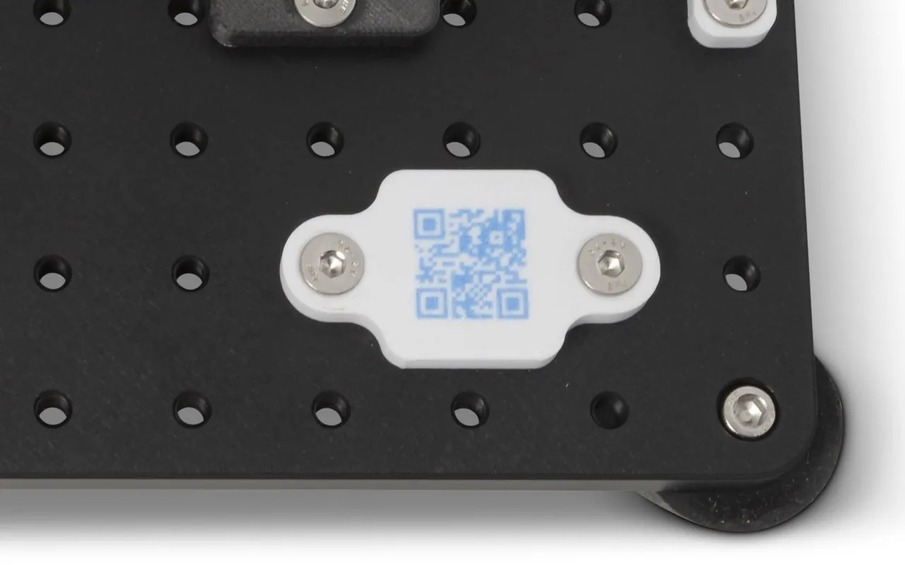 QR code embedded in a white APD part mounted on a fixture plate